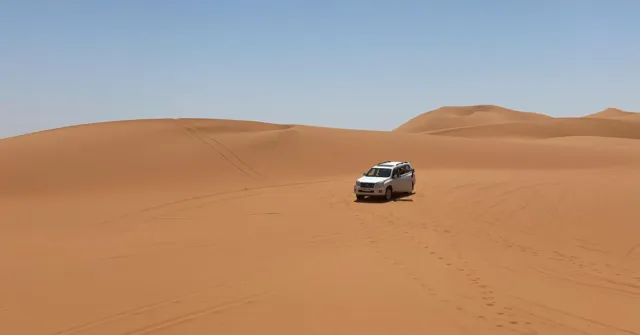 4x4 blanc roulant sur des dunes de sable orange lisses